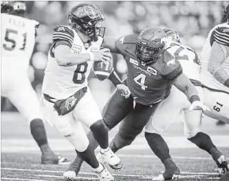  ?? JEFF MCINTOSH THE CANADIAN PRESS ?? Hamilton Tiger-Cats quarterbac­k Jeremiah Masoli, left, scrambles away from Stampeders’ Micah Johnson during second-half Canadian Football League action in Calgary on Saturday.