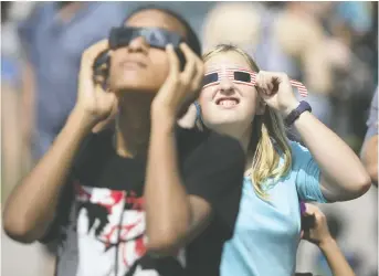  ?? DAX MELMER ?? Young astral observers use protective glasses to watch the 2017 solar eclipse along the city's waterfront. Police say if you're planning to view next Monday's eclipse by boat, ensure you have proper safety gear.