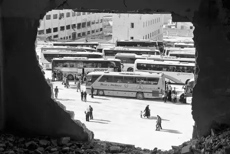  ??  ?? Syrians from the government-held towns of Fuaa and Kafraya, which have been under crippling siege for more than two years, reach with buses the edge of the rebel-held transit point of Rashidin outside government-held second city Aleppo. — AFP photo