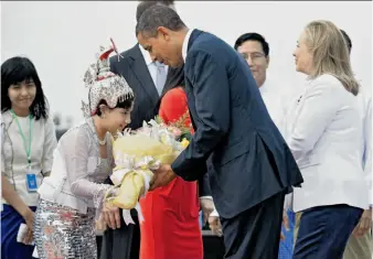  ?? Jewel Samad / AFP / Getty Images ?? A girl welcomes President Obama with flowers as he and Secretary of State Hillary Rodham Clinton (right) arrive at the airport in Rangoon, Burma, for an unpreceden­ted visit.