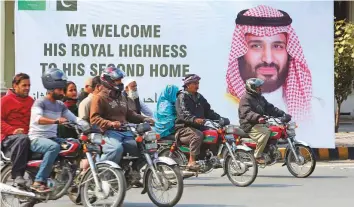  ??  ?? Above: Motorcycli­sts pass a portrait of Saudi Arabia’s Crown Prince Mohammad Bin Salman in Lahore yesterday. Mohammad Bin Salman is embarking on his first visit to Pakistan since becoming Crown Prince of Saudi Arabia in April 2017.