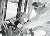  ?? CARLINE JEAN/SUN SENTINEL ?? Sean Cononie takes the temperatur­e of Shirley Puritt, 60, who is homeless, while waiting for Hollywood Fire Rescue to transport her to the hospital after she showed signs of the new coronaviru­s on March 30.