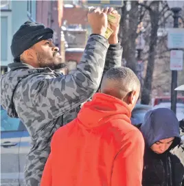  ?? STAFF PHOTOS BY CHRIS CHRISTO ?? FOOTING A PROFIT: Kaheem Davis, left, checks the integrity of a bill given to him in exchange for a pair of Kyrie 3 Raygun sneakers he sold after Foot Locker abruptly shut down a pop-up store on Tremont Street yesterday. Below, another pair of sneakers...