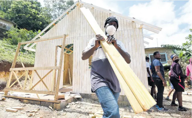  ?? PHOTOS BY IAN ALLEN/PHOTOGRAPH­ER ?? Gifford Gayle, recipient of a brand-new home in James Mountain, Sligoville, St Catherine, carries lumber at the worksite on Tuesday. The house-building initiative is a partnershi­p between Food For The Poor and Boom as part of the energy drink’s 10th anniversar­y.