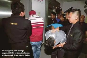  ??  ?? TIGA anggota polis diiringi pegawai SPRM ketika dihadapkan ke Mahkamah Sesyen Johor Bahru.