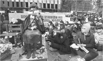  ??  ?? Protestors sit next ot the statue (left) of a teenage girl symbolisin­g former ‘comfort women’, who served as sex slaves for Japanese soldiers during World War II, during a weekly anti-Japan rally near the Japanese embassy in Seoul — AFP photo