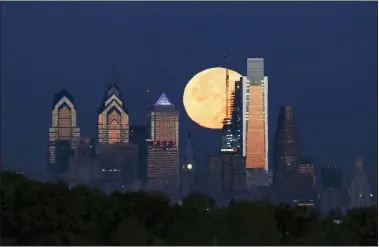  ?? JOSEPH KACZMAREK - THE ASSOCIATED PRESS ?? In this Nov. 14, 2016file photo a supermoon sets behind the Philadelph­ia skyline. Bird Safe Philly announced on Thursday, March 11, 2021, that Philadelph­ia is joining the national Lights Out initiative, a voluntary program in which as many external and internal lights in buildings are turned off or dimmed at night during the spring and fall bird migration seasons. Millions of birds annually migrate through Philadelph­ia during spring and fall and many are killed when they fly into buildings, confused by the bright artificial lights and glass.