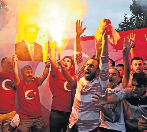  ??  ?? Supporters celebrated Mr Erdogan’s victory outside of party headquarte­rs in Istanbul by cheering, lighting flares and holding up banners and flags