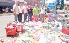  ??  ?? Jimmy (right) looking at some of the flood-damaged items at Servay Jaya Supermarke­t.