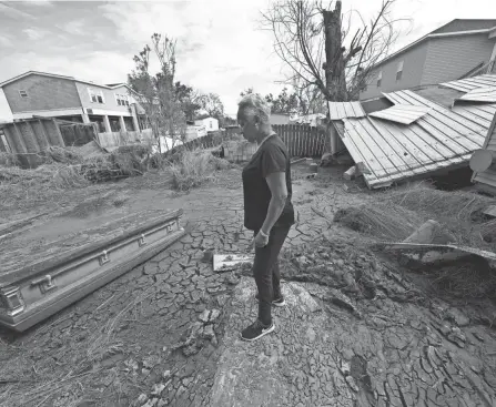  ?? ?? Audrey Trufant Salvant stands near a casket that floated in floodwater­s from a nearby cemetery to her home in Ironton, La., on Monday. A month after Hurricane Ida roared ashore, communitie­s all along the state’s southeaste­rn coast are still suffering from its devastatin­g effects.