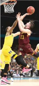  ?? RONALD MARTINEZ/ GETTY IMAGES ?? Junior guard Clayton Custer, attempting a shot over Michigan’s Jaaron Simmons in the second half, had 15 points for the Ramblers.