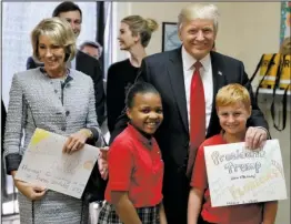  ?? The Associated Press ?? TRUMP: President Donald Trump and Education Secretary Betsy DeVos stand with fourth graders Janayah Chatelier, 10, left, Landon Fritz, 10, after they received cards from the children during a tour of Saint Andrew Catholic School on Friday in Orlando,...