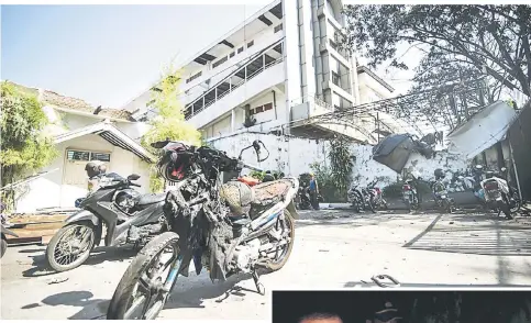  ?? — AFP photo ?? A damaged motorcycle is seen outside the Gereja Pantekosta Pusat Surabaya (Surabaya Centre Pentecosta­l Church) in Surabaya following a blast outside the church a day earlier.