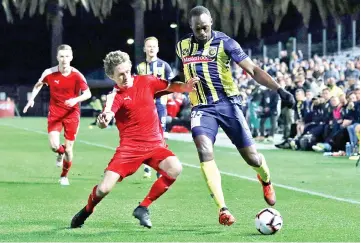  ?? — AFP photo ?? Bolt (right) playing for A-League football club Central Coast Mariners, fights for the ball with a player from a a Central Coast amateur selection team during a pre-season practice football match in Gosford, New South Wales.