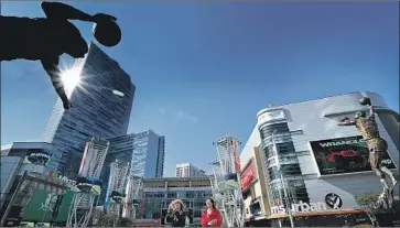  ?? Mel Melcon Los Angeles Times ?? JOYLING LEE and Minting Luo, visiting from China in 2018, look at a statue of former Lakers star Magic Johnson outside Staples Center. The arena is home to the NBA’s Lakers and Clippers and the NHL’s Kings.