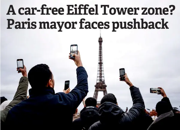  ?? — AFP photo ?? People take pictures with their mobile phones at the Trocadero Square with the Eiffel Tower in the background in Paris.