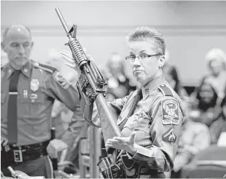  ?? Jessica Hill / Associated Press file ?? Barbara Mattson of the Connecticu­t State Police displays a Bushmaster AR-15 rifle in 2013 at a legislativ­e hearing. That is the same make and model of gun used in the Sandy Hook School shooting. Gun maker Remington was cleared of wrongdoing in the case.