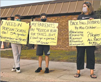  ?? JESSE WRIGHT/DAILY SOUTHTOWN PHOTOS ?? Jayson and Drew stand with their mom, Valerie Miller, protesting their school’s reopening plan at the Homer District 33C School Board meeting.