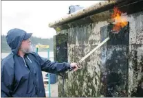  ??  ?? A volunteer burns some of the two tonnes of marine organisms off a Japanese dock in Oregon.