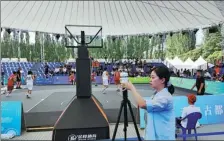  ?? HU JIANGBO / FOR CHINA DAILY ?? A worker adjusts meteorolog­ical equipment while a game of basketball is played at the national games.