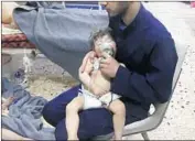  ?? Syria Civil Defense via Associated Press ?? A WORKER aids a toddler after an apparent gas attack in Duma, Syria, in an image taken from video.