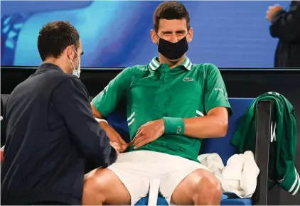  ??  ?? Novak Djokovic receives treatment during his third round match against United States' Talyor Fritz