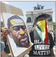  ?? (AP/Kathy Willens) ?? A man holds up an image of George Floyd and wears a Guyanese flag as face protection Sunday during a rally led by Caribbean Americans at Grand Army Plaza in the Brooklyn borough of New York.