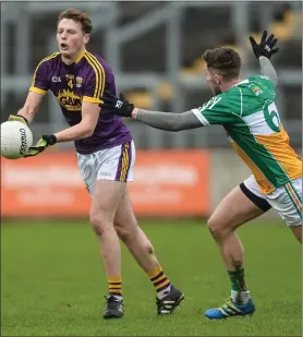  ??  ?? Mark Rossiter delivers a handpass as Offaly defender Cian Donohue moves in.