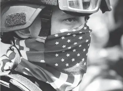  ?? MARK GRAVES / THE OREGONIAN VIA THE ASSOCIATED PRESS ?? A protester participat­es in a rally Saturday in Portland as small scuffles broke out and police deployed “flash bang” devices and other means to disperse hundreds of right-wing and self-described anti-fascist protesters.