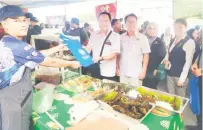  ?? ?? SAMPAIKAN MESEJ: Dr Johnny menyerahka­n risalah berkaitan keselamata­n makanan kepada peniaga di Bazar Ramadan MADANI Medan Niaga Satok.