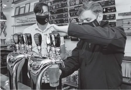  ?? JOE GIBBONS • THE TELEGRAM ?? Premier Andrew Furey (right) pours himself a pint of Iceberg beer at Quidi Vidi Brewery in St. John’s on Friday as the brewery’s sales and marketing director, Justin Fong, looks on.