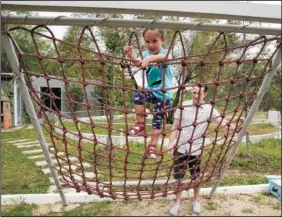  ?? (AP/Sakchai Lalit) ?? Poulin (right) watches Rylae-Ann climb a rope ladder Jan. 14 at a playground in Bangkok.