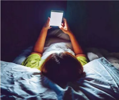  ?? MEDITERRÁN­EO ?? Un niño visualiza contenidos en su móvil acostado en la cama durante la noche.