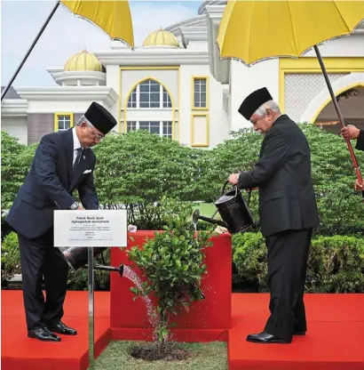  ?? ?? Green vision: sultan abdullah watering the tree planted by Tuanku muhriz (right) at the compound of the Istana negara in Kuala Lumpur. — bernama