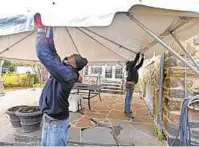  ?? KENNETH K. LAM/BALTIMORE SUN ?? Loane Brothers tent techs Tavon Ireland, left, and Mark King set up a heated tent in the patio of a customer’s home.