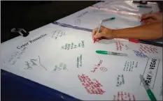  ?? Nikolas Samuels
/The Signal ?? (Above) People sign giant get-well cards for the injured in the Las Vegas shooting during a vigil held at Santa Clarita Marketplac­e Park in Valencia on Wednesday.