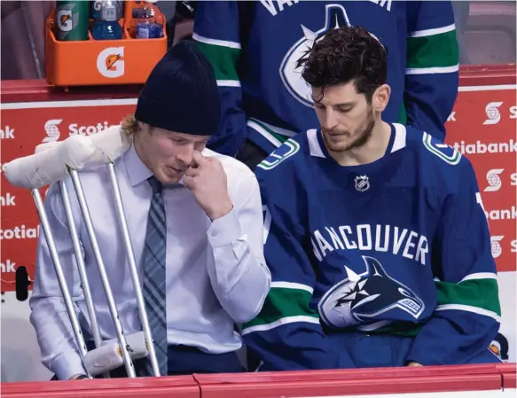  ?? THE CANADIAN PRESS/JONATHAN HAYWARD PHOTO ?? Vancouver Canucks right wing Brock Boeser came back to the bench in crutches to speak to Vancouver Canucks centre Nic Dowd following a loss to the Calgary Flames in Vancouver on Sunday. Boeser took a shot off his left foot early in the second period of...