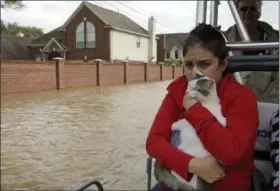  ?? CHARLIE RIEDEL — ASSOCIATED PRESS ?? Jannett Martinez holds her cat, Gigi, on Tuesday as she rides a boat out of her flooded Houston neighborho­od.