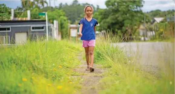  ?? Photo: Leon Lord ?? Kristelle Tuitoga 8, passes unattended grass normally cut by Nasinu Town Councial along Vere Street at Laucala Beach on January 4, 2021.