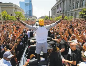  ?? Gene J. Puskar / Associated Press ?? Forward LeBron James acknowledg­es a crowd of hundreds of thousands as his Rolls Royce ride crawls through the streets of Cleveland.