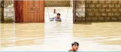  ??  ?? KARACHI: Young boys wade and play among floodwater­s during heavy monsoon rains in Karachi yesterday. — AFP