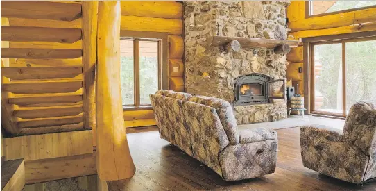  ?? PHOTOS: PERRY MASTROVITO ?? Attached to large timbers, the half-log steps lead down from the mezzanine to the living room, which features an imposing natural stone fireplace.