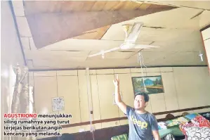  ??  ?? AGUSTRIONO menunjukka­n siling rumahnya yang turut terjejas berikutan angin kencang yang melanda.