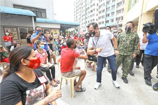  ?? PHOTOGRAPH COURTESY OF PNA ?? MANILA Mayor Francisco ‘Isko Moreno’ Domagoso greets one of the fire victims with an elbow bump during his visit to the evacuation center at Jose Abad Santos Elementary School in Binondo, Manila on Wednesday. Domagoso on the spot gave a job to Jennifer Arizala, whose husband and their four sons died in a fire that gutted their house in Parola, Tondo over the weekend.