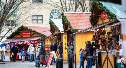  ??  ?? People walk through wooden chalets at the Peoples Gas Holiday Market on Wednesday in Downtown. They were forced to close Friday due to a surge in COVID-19.