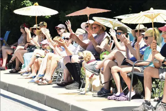  ?? Ernest A. Brown photo ?? Shade umbrellas were in abundance as families applaud the passing parade in Arnold Mills on Monday.