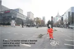  ?? ?? Asanitatio­n worker sweeps a deserted road in Xi’an, which has been locked down since Dec 22.