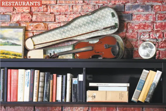  ?? Photos by Paul Chinn / The Chronicle ?? A violin is displayed on a bookshelf at Sláinte in Oakland, where a regular jam session breaks out on Thursday evenings and some Sundays.