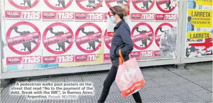  ?? Picture: REUTERS ?? A pedestrian walks past posters on the street that read “No to the payment of the debt. Break with the IMF”, in Buenos Aires, Argentina.