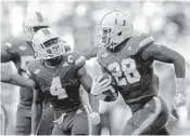  ?? JOHN MCCALL/STAFF PHOTOGRAPH­ER ?? UM cornerback Michael Jackson celebrates with teammates after his second quarter intercepti­on on Saturday.